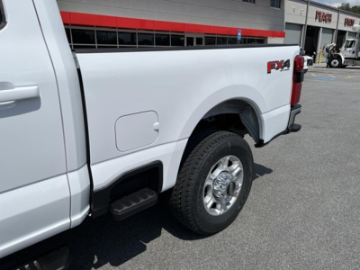 Ford pickup truck rear quarter showing FX4 off-road decal on the bed side and wheel, with fuel door and rear quarter panel visible.