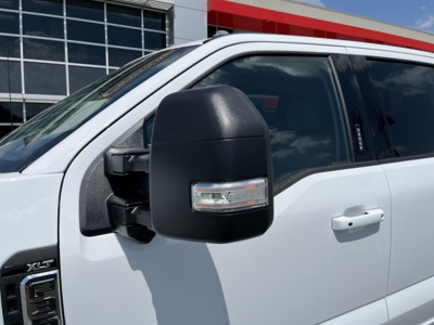 Ford F-350 pickup truck exterior close-up showing large black side mirror and front door; side window with reflection.