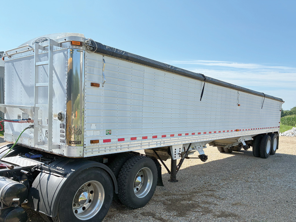 Tri-axle aluminum hopper bottom grain trailer with rear access ladder and side panels, white/metallic finish, VIN XB095125.