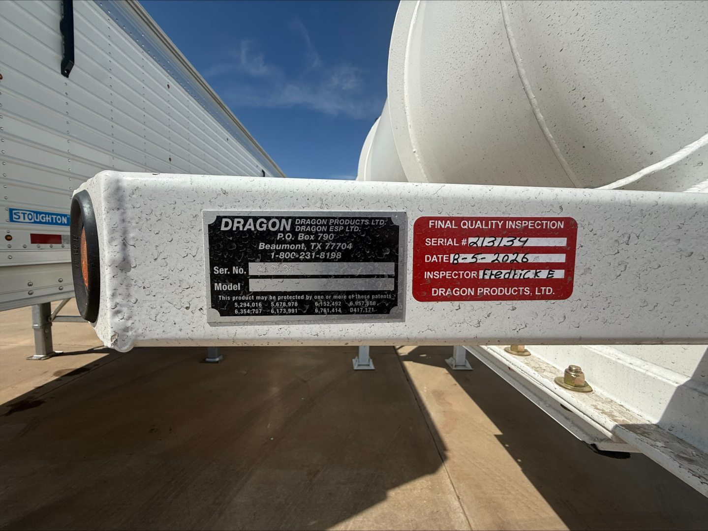 Dragon trailer hitch indicating Dragon Products serial/model plate and final quality inspection label attached to a white cylindrical tank on a trailer.