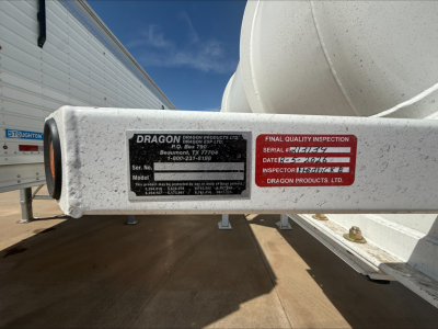 Dragon trailer hitch indicating Dragon Products serial/model plate and final quality inspection label attached to a white cylindrical tank on a trailer.