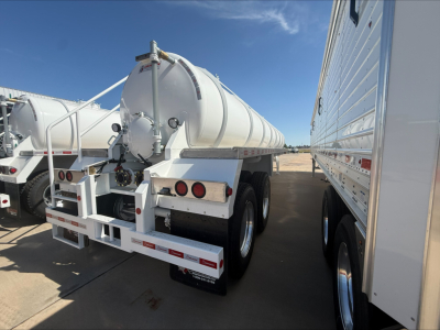 Vacuum trailer rear view showing cylindrical tank and taillights with dual-axle configuration in a lot.