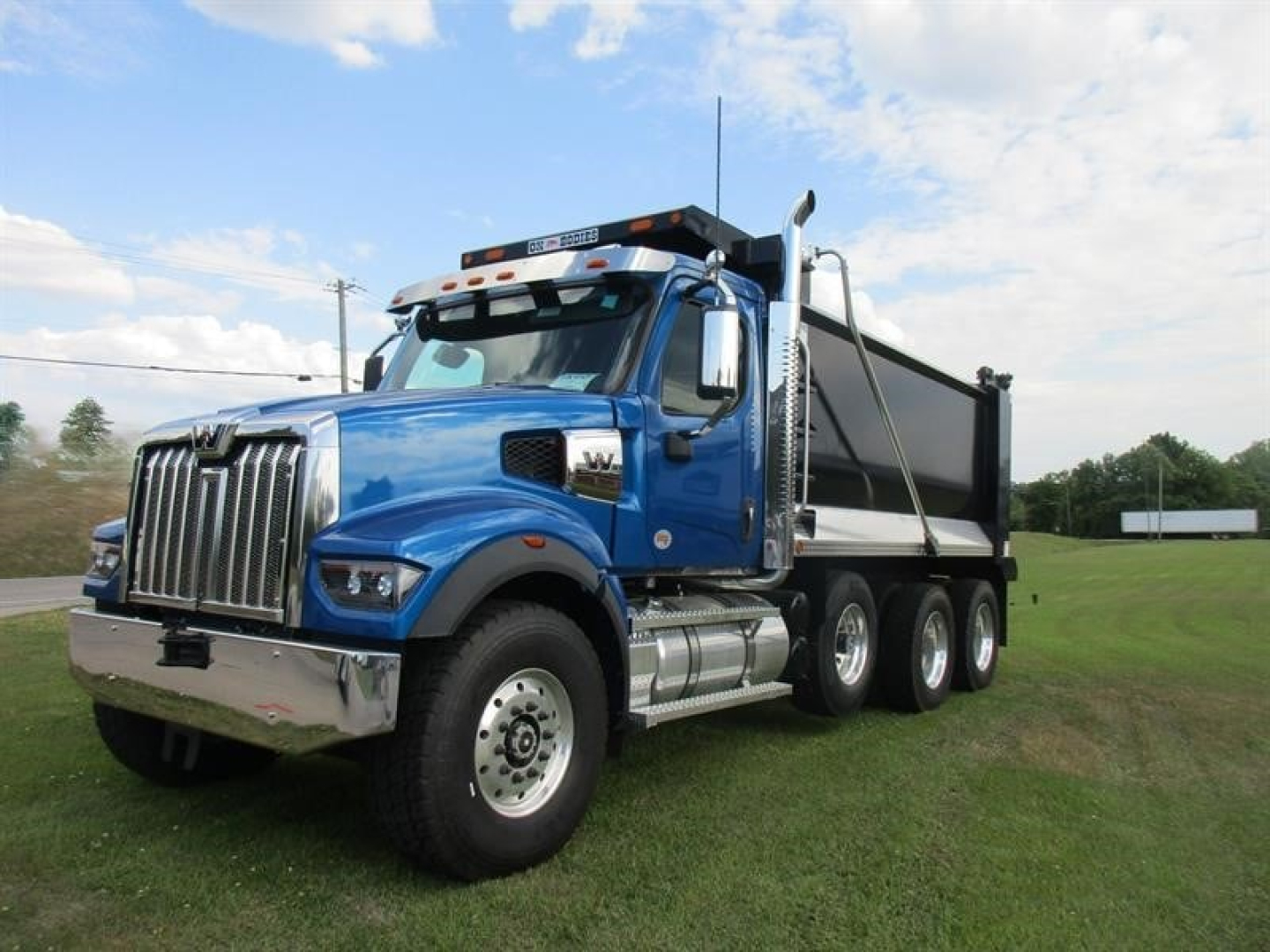 Western Star 49X dump truck in blue, side view, with chrome grille and dump bed visible.