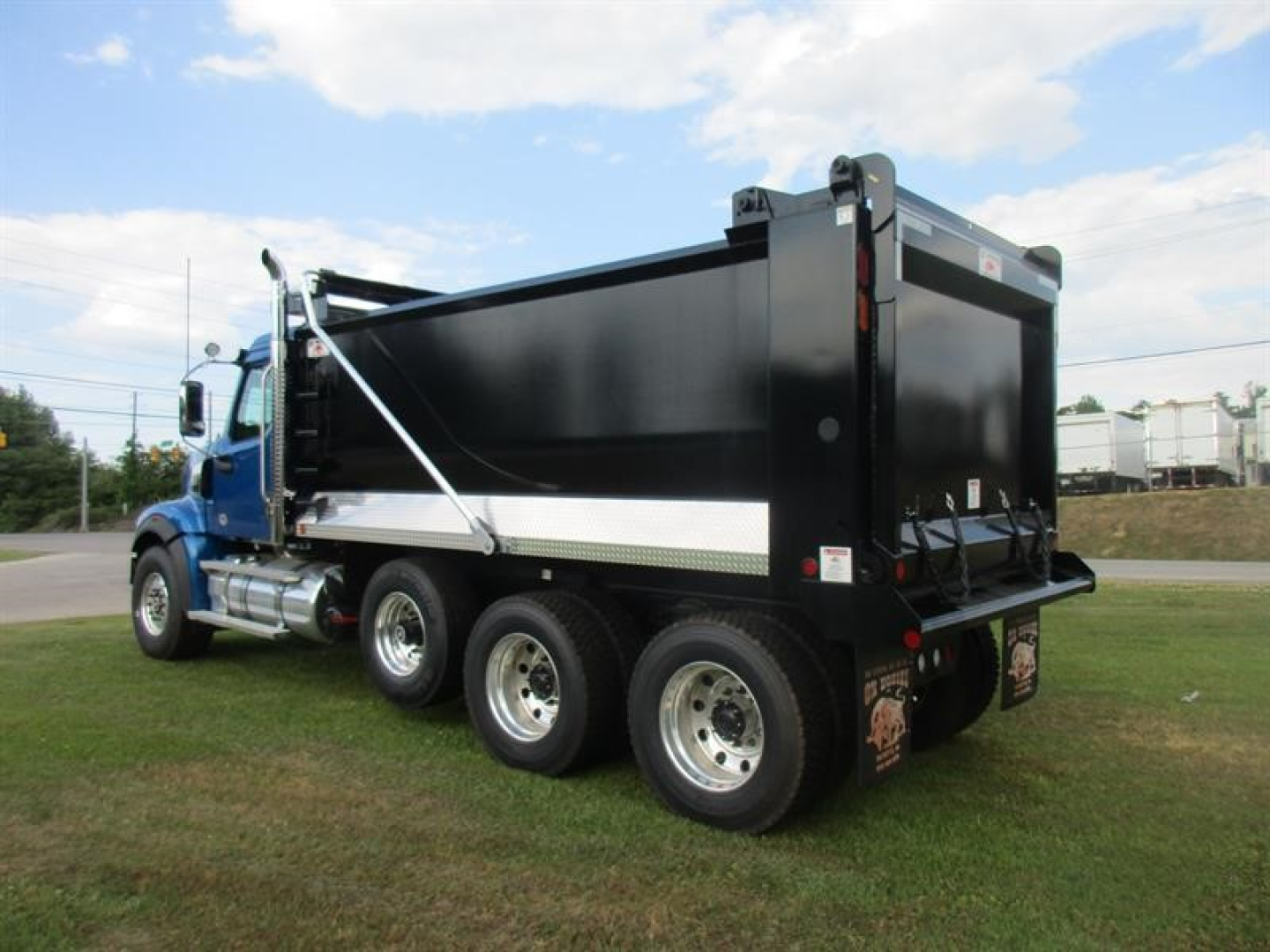 Western Star 49X dump truck in profile view showing black dump bed, blue cab, tandem rear axles, hydraulic hoist, and side steps. No visible text captured on components.