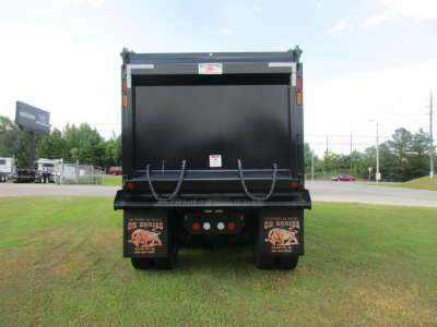 Dump truck rear showing mud flaps with graphic, rear bumper with lights, and open cargo bed of a new Western Star 49X dump truck.