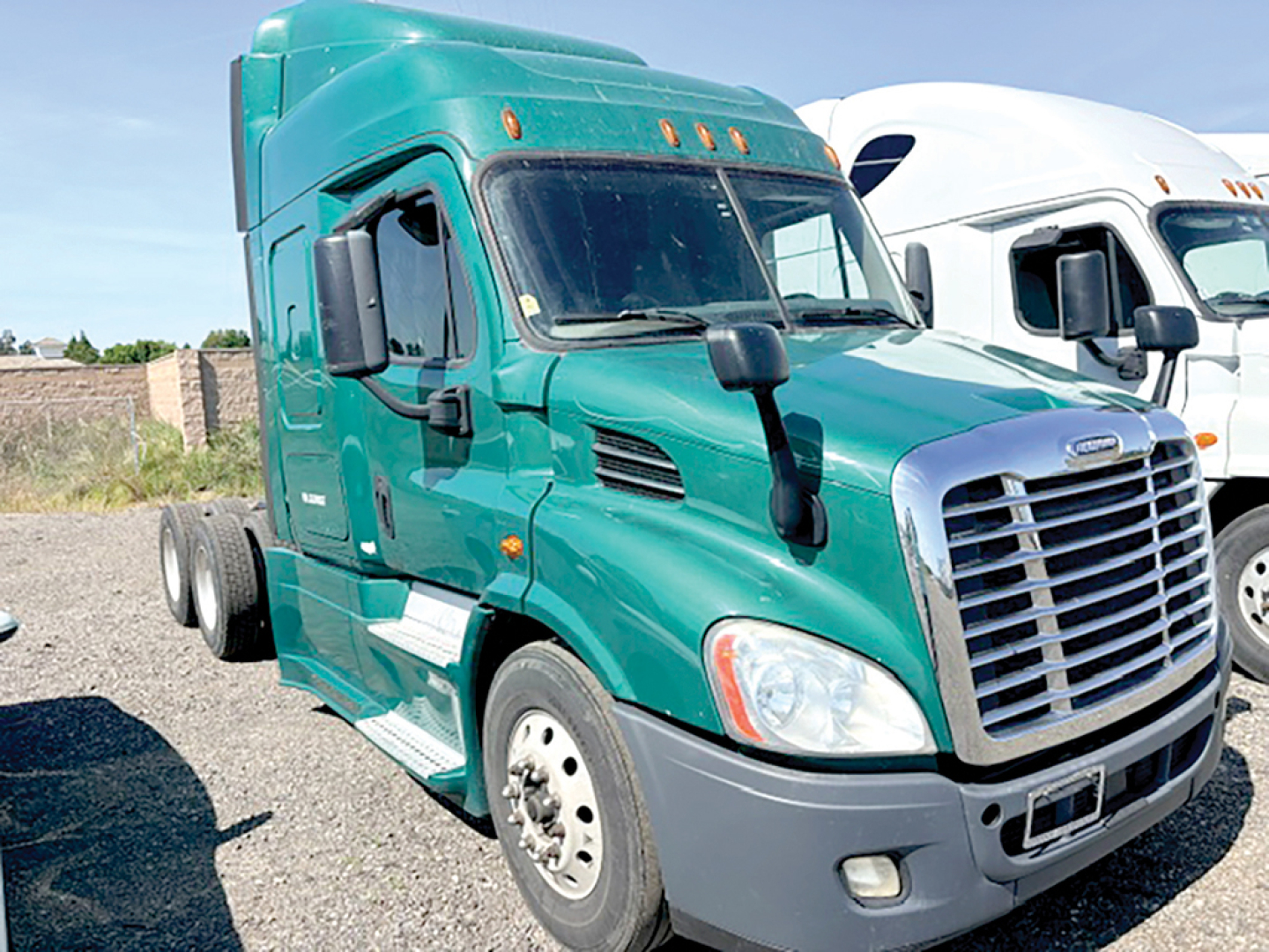 Truck cab side view showing a green 2018 Freightliner Cascadia113 with grille, mirrors, and daytime running lights.