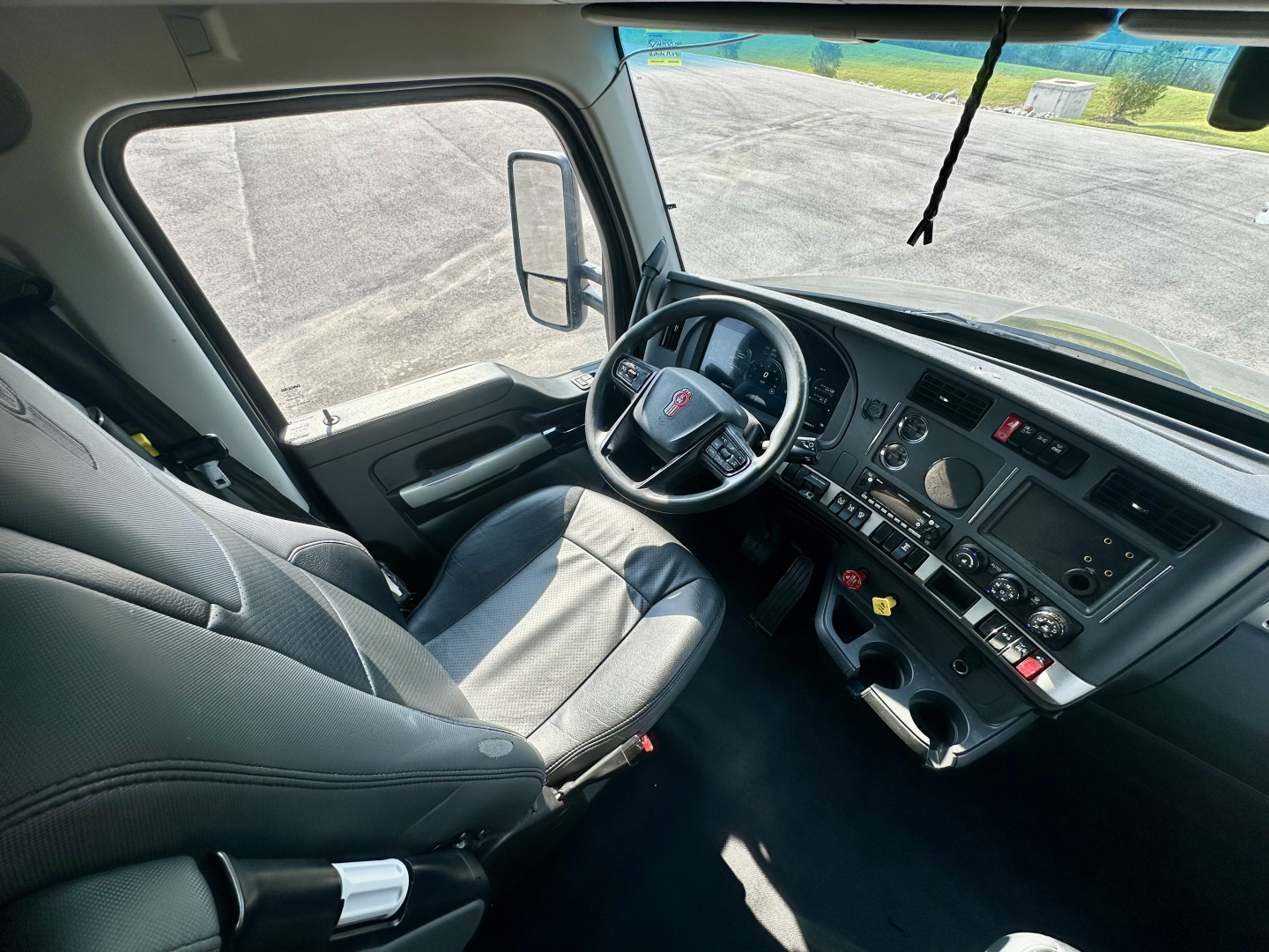 Kenworth T680 cabin interior with steering wheel, dashboard, and driver seat in view. Visible instruments and controls on dash.