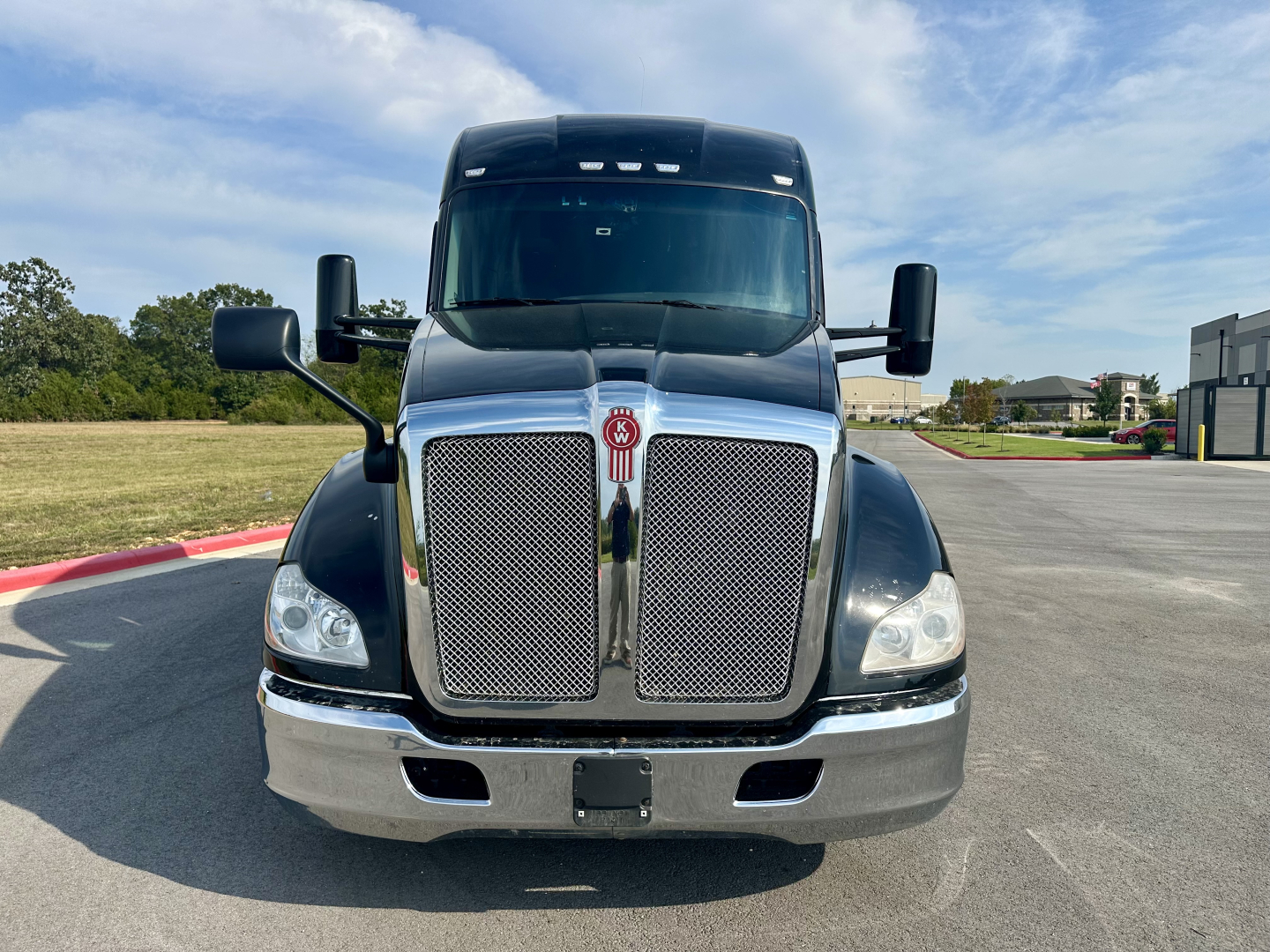 Kenworth T680 truck front view showing large chrome grille and bumper with headlights and mirrors.