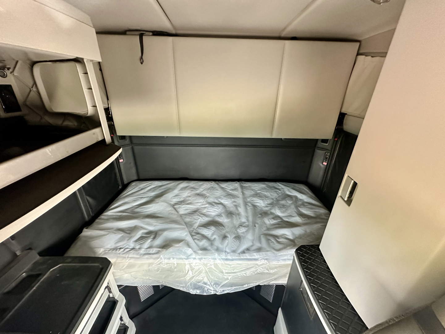 Kenworth T680 sleeper cab interior bed area with bunk and side storage compartments visible.
