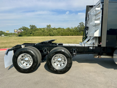 Kenworth T680 tractor chassis showing dual rear axles and part of the sleeper cab, with chrome wheels and chassis frame visible.