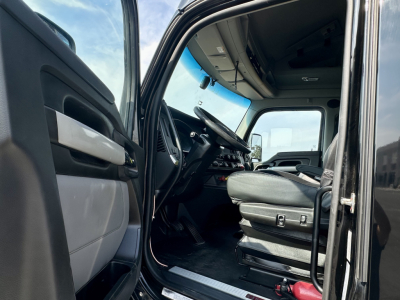 Kenworth T680 truck interior cab view from driver door showing steering wheel, dashboard, and driver seat.