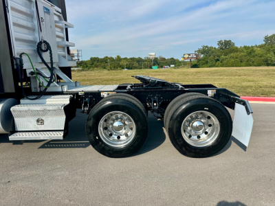 Kenworth T680 tractor rear dual rear wheels and fifth wheel assembly visible in side view. Chrome wheels, black chassis, aluminum tool boxes, white mud flaps, no cab in frame.