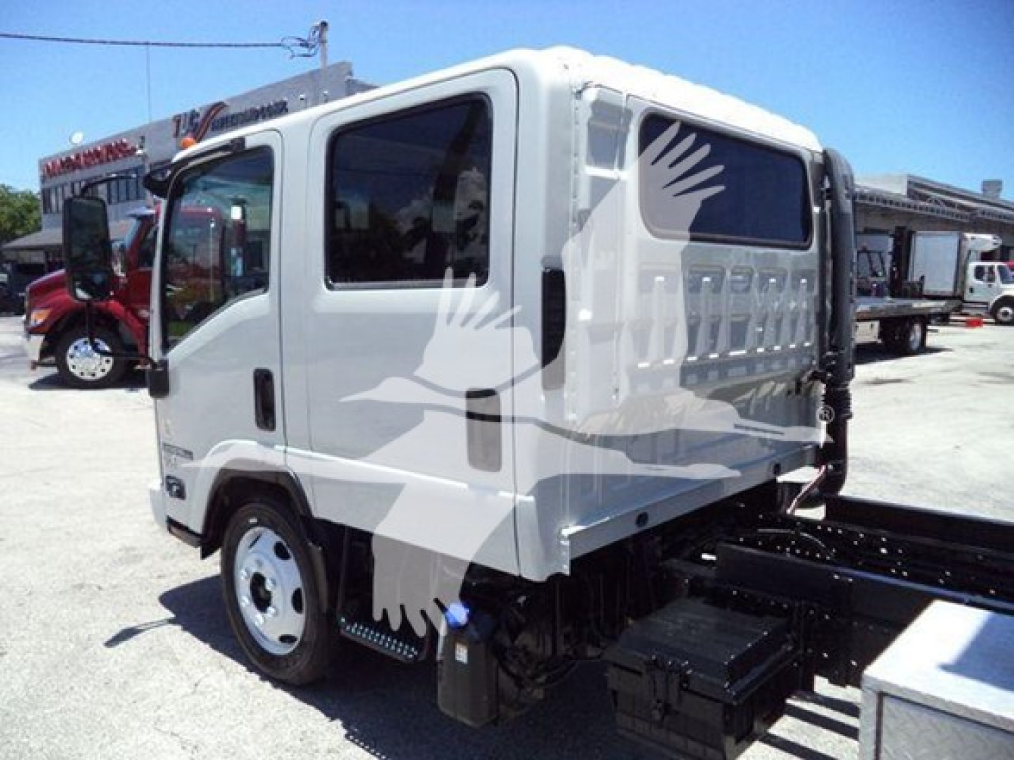 Isuzu NPR-HD cab front-left view showing side steps and chassis with white body and graphic bird decal.