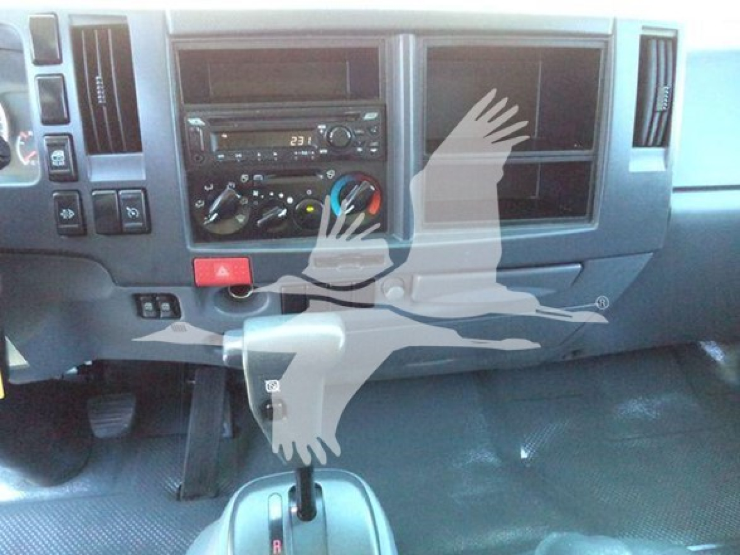 Isuzu NPR HD dash showing steering column, radio, climate controls, and gear shifter in a used truck interior.