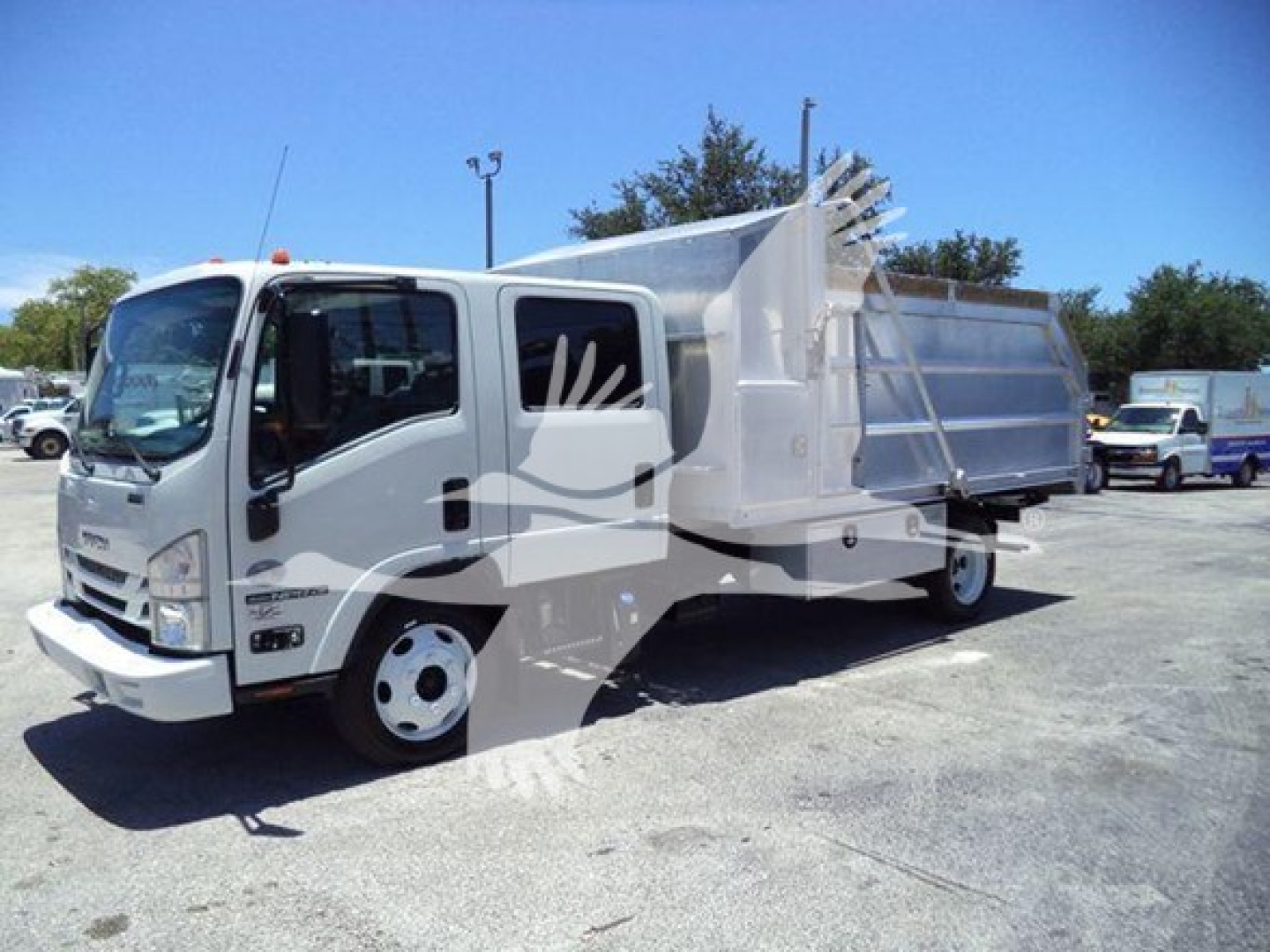 Isuzu NPR-HD dump truck in service shown from front-left side with dump bed and hydraulic tailgate.