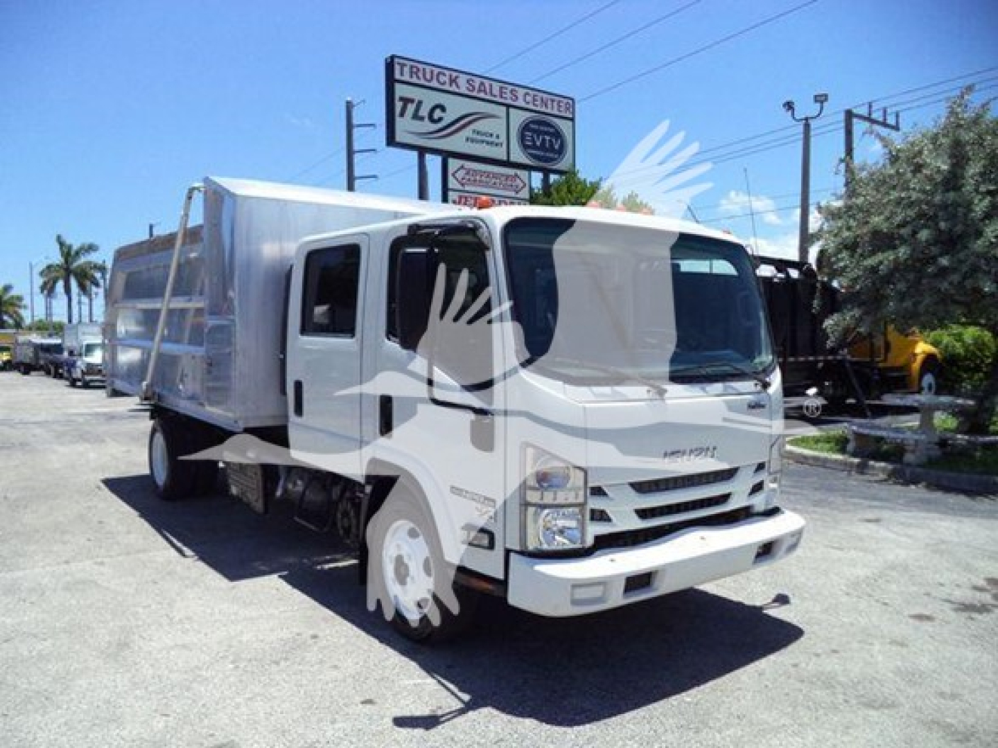 Isuzu NPR HD dump truck in a dealership lot with white cab and cargo bed, front view, chrome grille and large side mirrors.