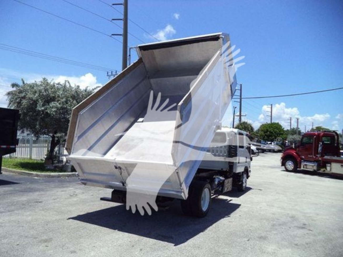 Isuzu NPR-HD dump truck with rear dump bed raised, side view showing tilting bed and chassis.