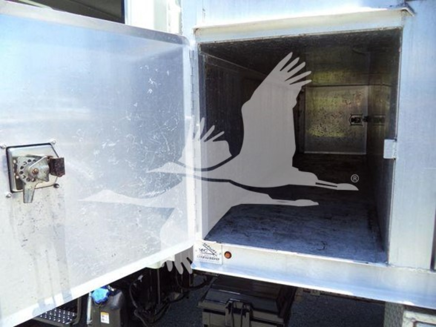 Isuzu NPR HD dump truck cargo area door open showing interior of cargo box and a stylized bird graphic on the door.