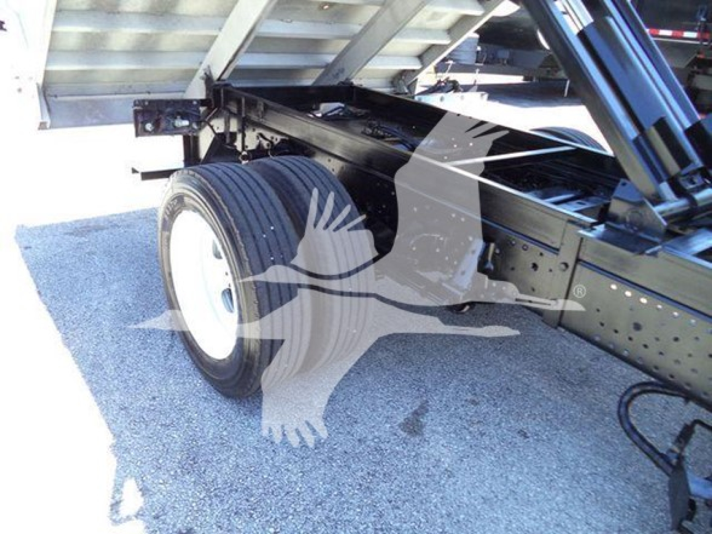Isuzu NPR HD dump truck chassis showing rear wheel and dump bed linkage and frame components.