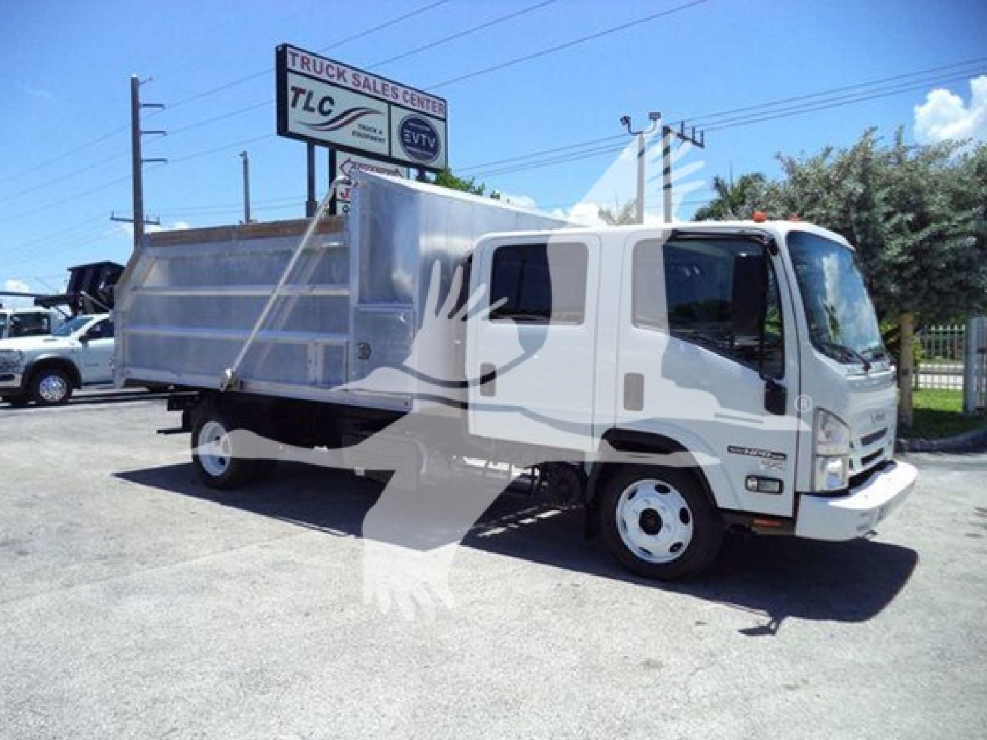Isuzu NPR HD dump truck side view with a large metal bed, cab in white, in a lot