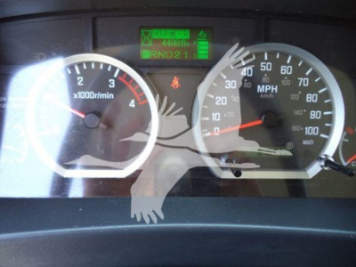 Isuzu NPR HD dashboard showing  at-speed gauge cluster, green diagnostic display, and odometer; front view of instrument panel with tachometer and speedometer.