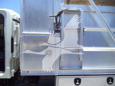 Isuzu NPR-HD dump truck side view showing aluminum cargo body with access door and steps.