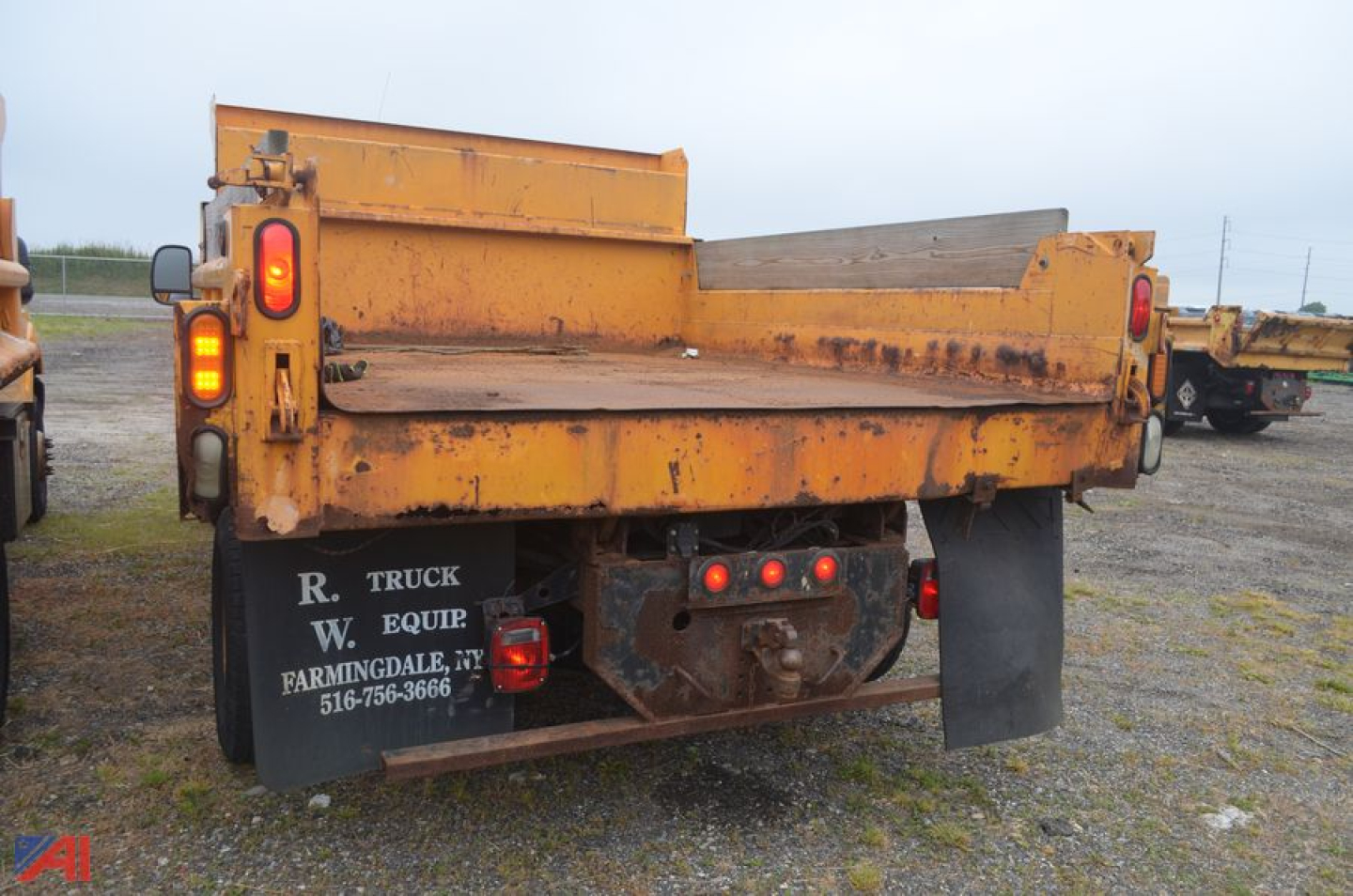 Rear view of a yellow Ford F-350 Super Duty dump truck bed showing taillights, hydraulic pump area, and tailgate hinges.