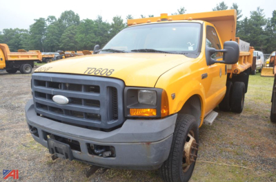 Ford F-350 Super Duty dump truck in a field, yellow cab, black grille, TD608 printed on hood, hydraulic dump bed raised.
