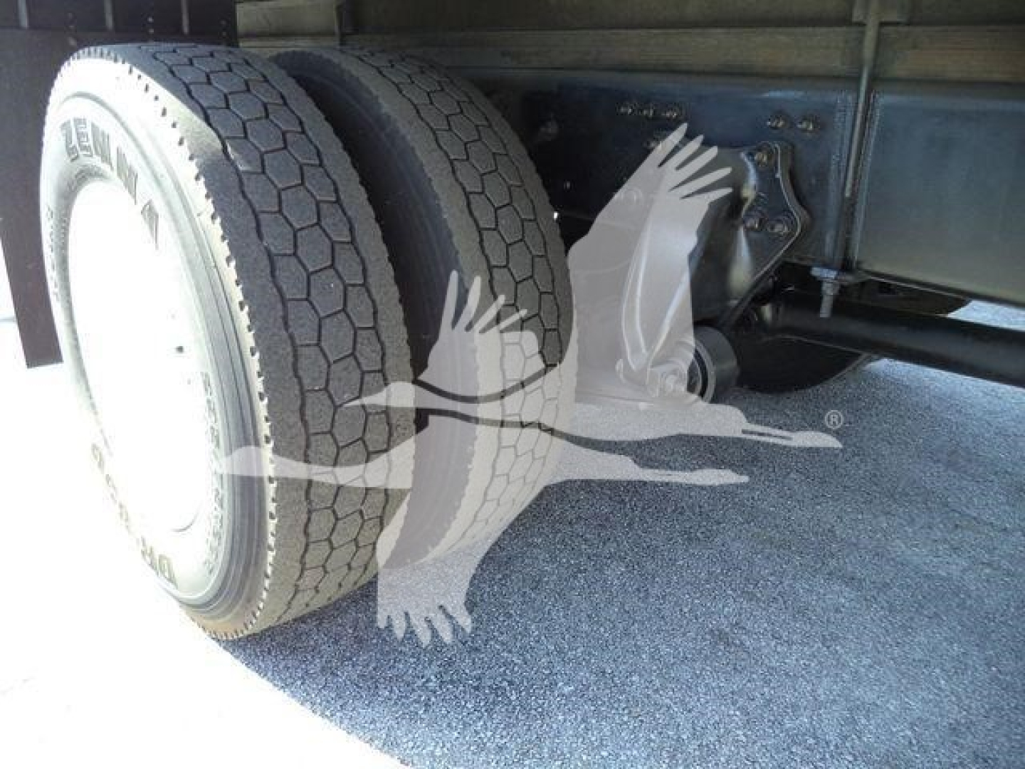 Freightliner M2 106 chassis showing dual rear tires and undercarriage with refrigeration truck components.