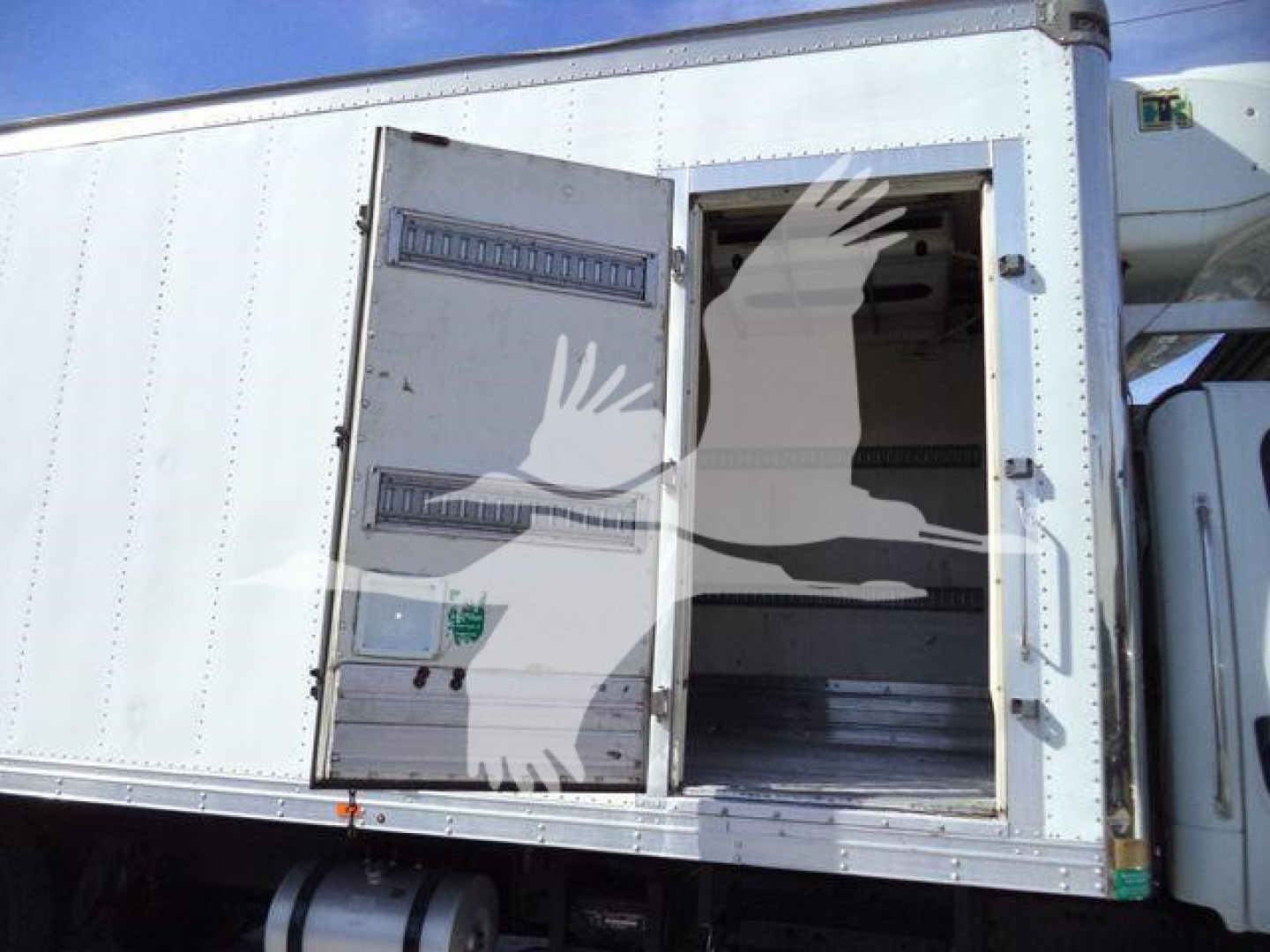 Rear/side view of a Freightliner M2 106 refrigerated truck with rear cargo doors open showing empty metal interior.