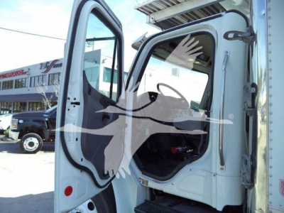 Cabin of a Freightliner M2-106 truck with door open, interior view showing steering area and cab entry.