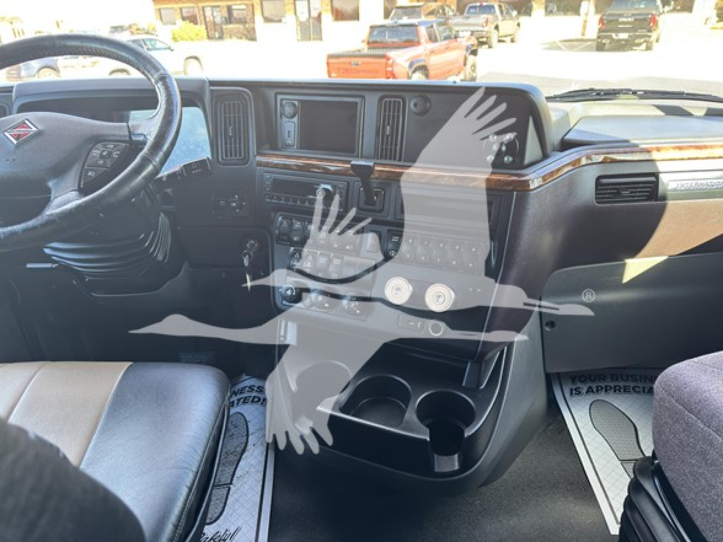Interior of 2018 International LT cab showing steering wheel, dashboard, center console with cups holders and controls.