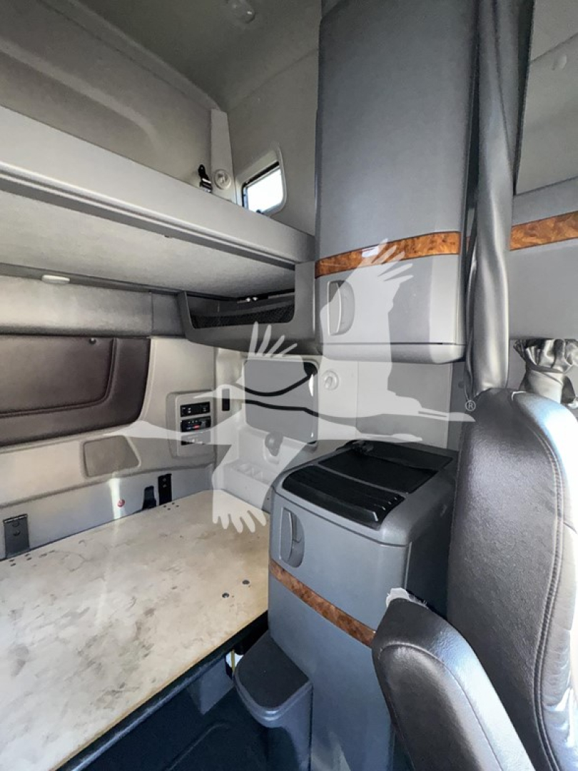 Interior sleeper cab of a 2018 International LT showing bunk area, small cabinet, and workspace with wood trim.