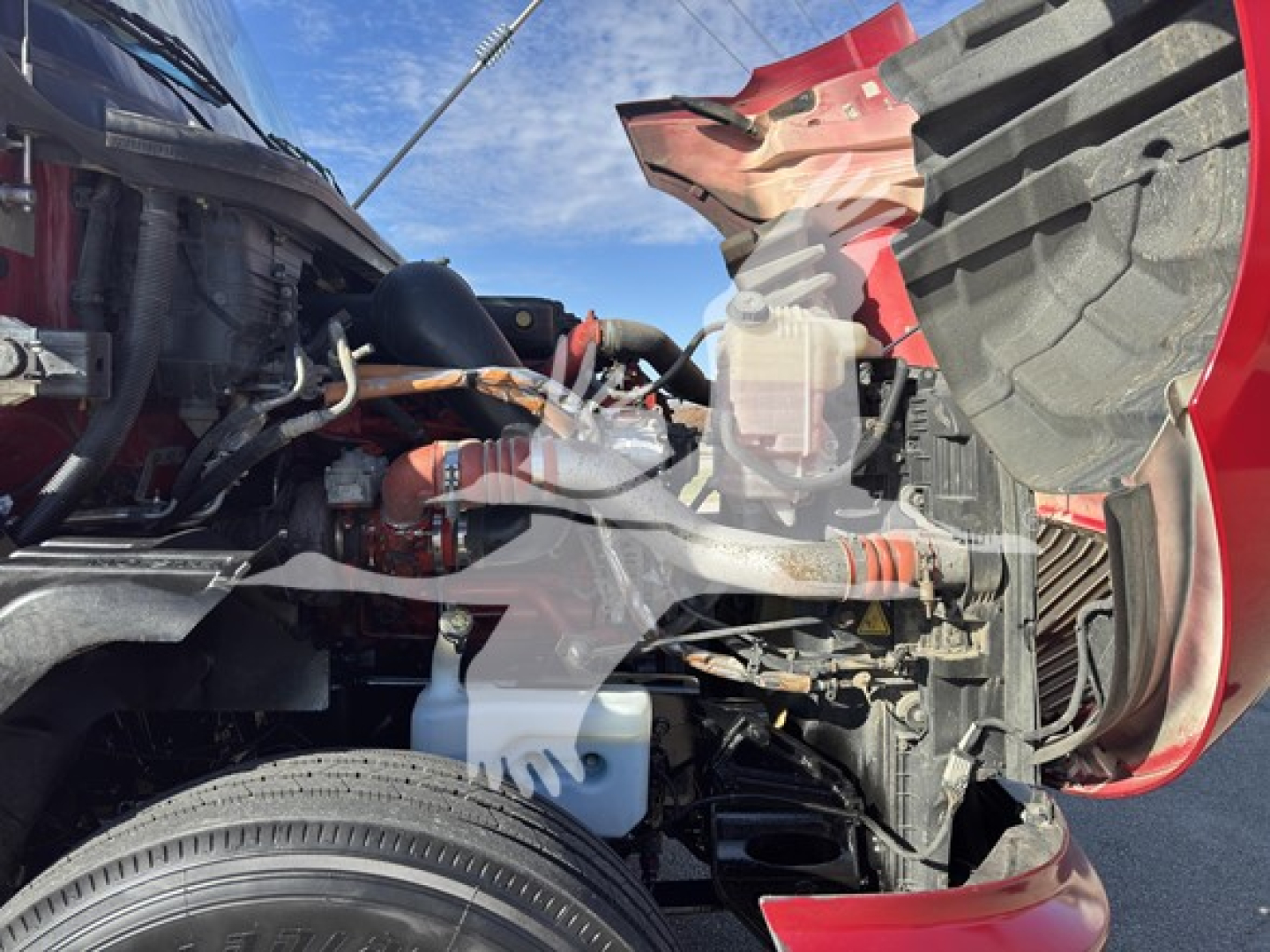 Truck engine bay and front left wheel well of a 2018 International LT with visible coolant reservoir, hoses, and engine components.