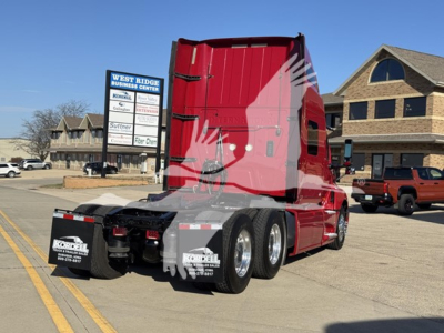 Truck rear view showing red cab and dual rear axles with mud flaps and license plate area.