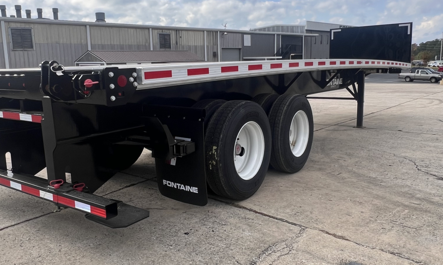 Fontaine 37' flatbed trailer with a front forklift lift kit, dual rear axles, white wheels, and black frame with reflective tape.