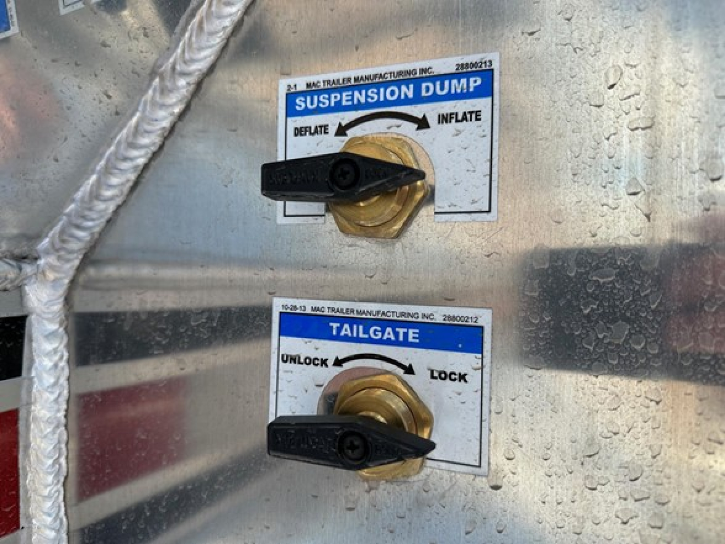 Mac trailers showing suspension dump and tailgate control levers on a half-round aluminum end dump trailer.