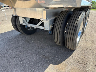 Mac Macsimiser half round aluminum end dump trailer rear wheels and undercarriage showing dual-axle setup and aluminum frame.