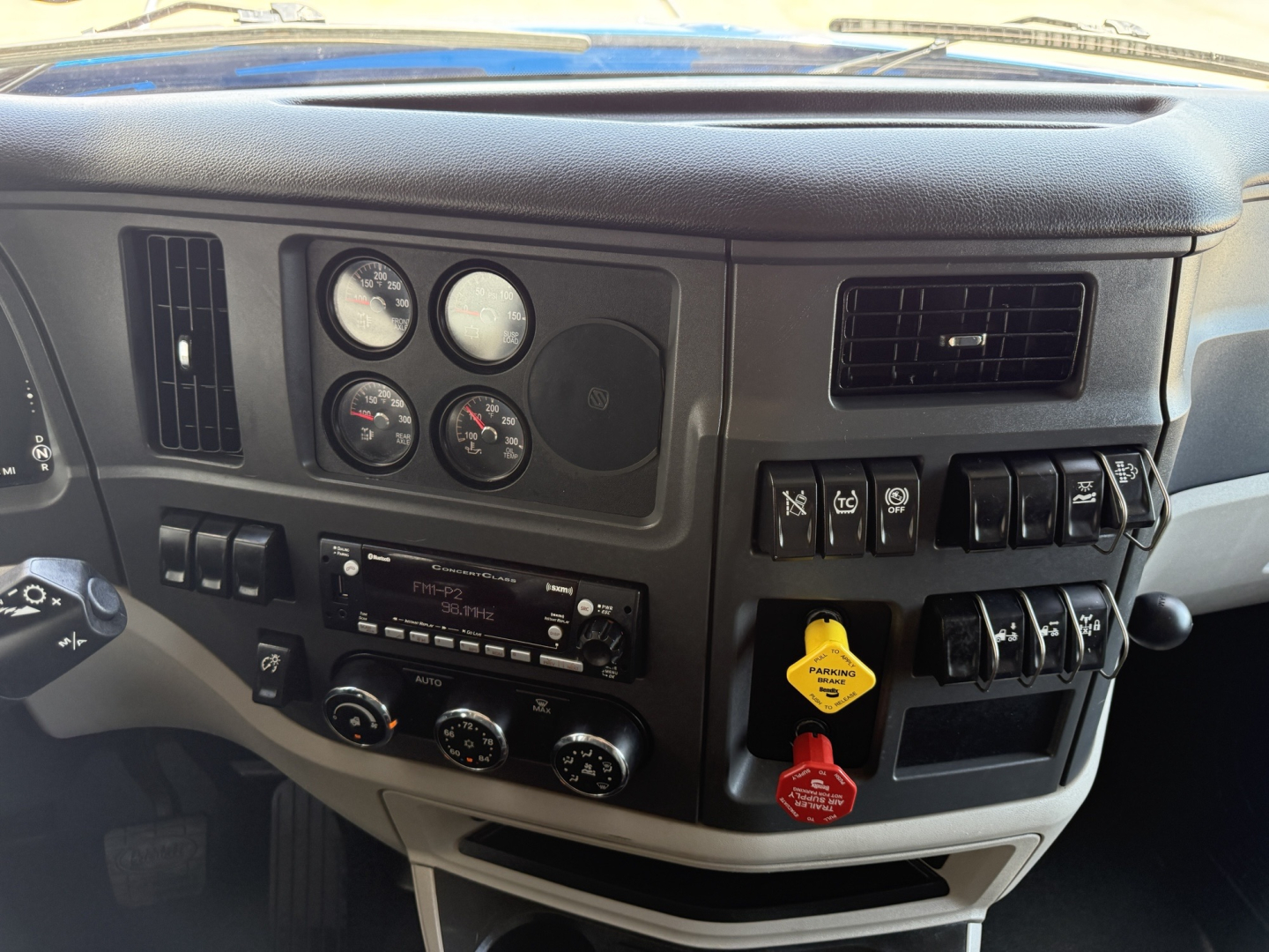 Peterbilt 579 dashboard showing instrument cluster, switches, and controls; visible labels include various round gauges, ignition key area with yellow and red keys, and radio/Cassette unit.