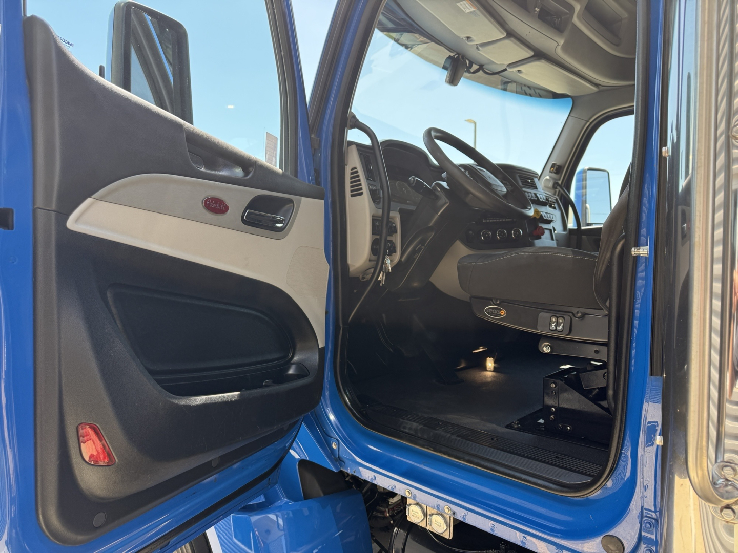 Peterbilt 579 truck interior view from open driver door showing dash and steering wheel.