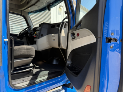 Peterbilt 579 truck interior view with open driver door, dashboard, steering wheel, and entry area visible.