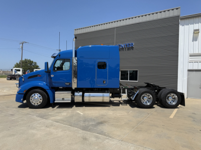 Peterbilt 579 tractor in blue, side view showing sleeper cab and dual rear axles, no visible damage.
