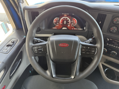 Peterbilt steering wheel and dashboard inside cab showing digital instruments and controls.