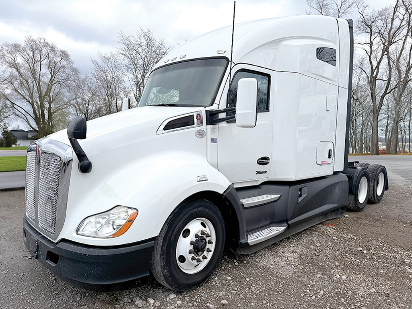 Kenworth T680 semi-truck 2022 white cab with sleeper, side view showing front grille, headlights, wheel, and dual rear axles.