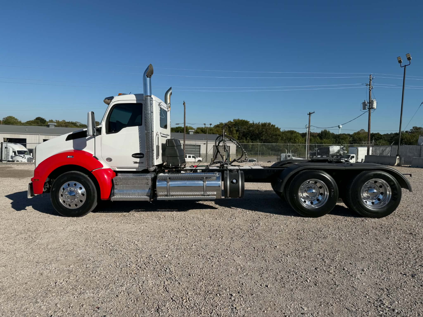 Kenworth T880 daycab chassis side view showing cab with red front fenders, chrome fuel tanks, dual rear axles, and exhaust stack.