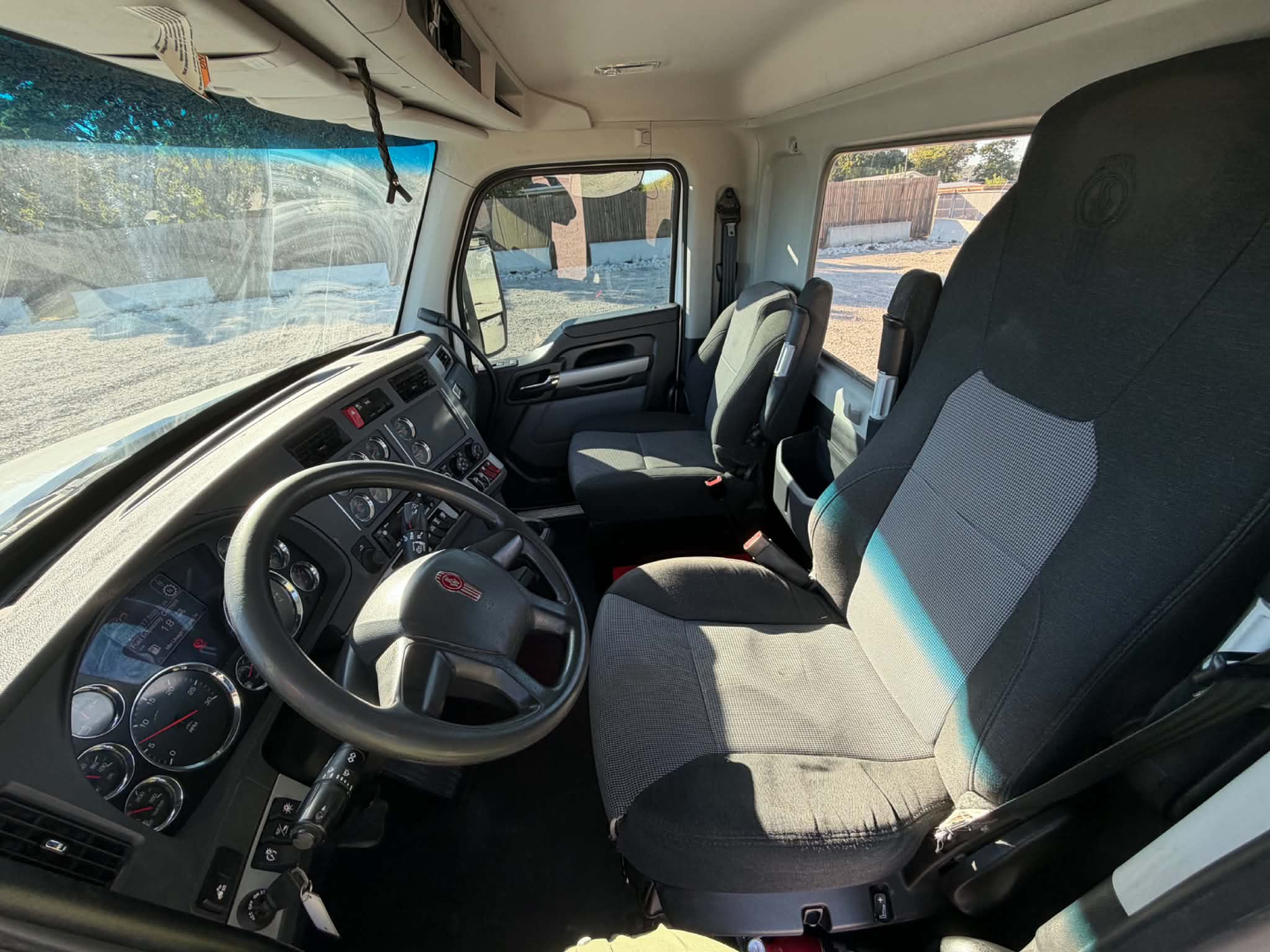 Kenworth T880 cab interior showing steering wheel, dashboard, and front seats.