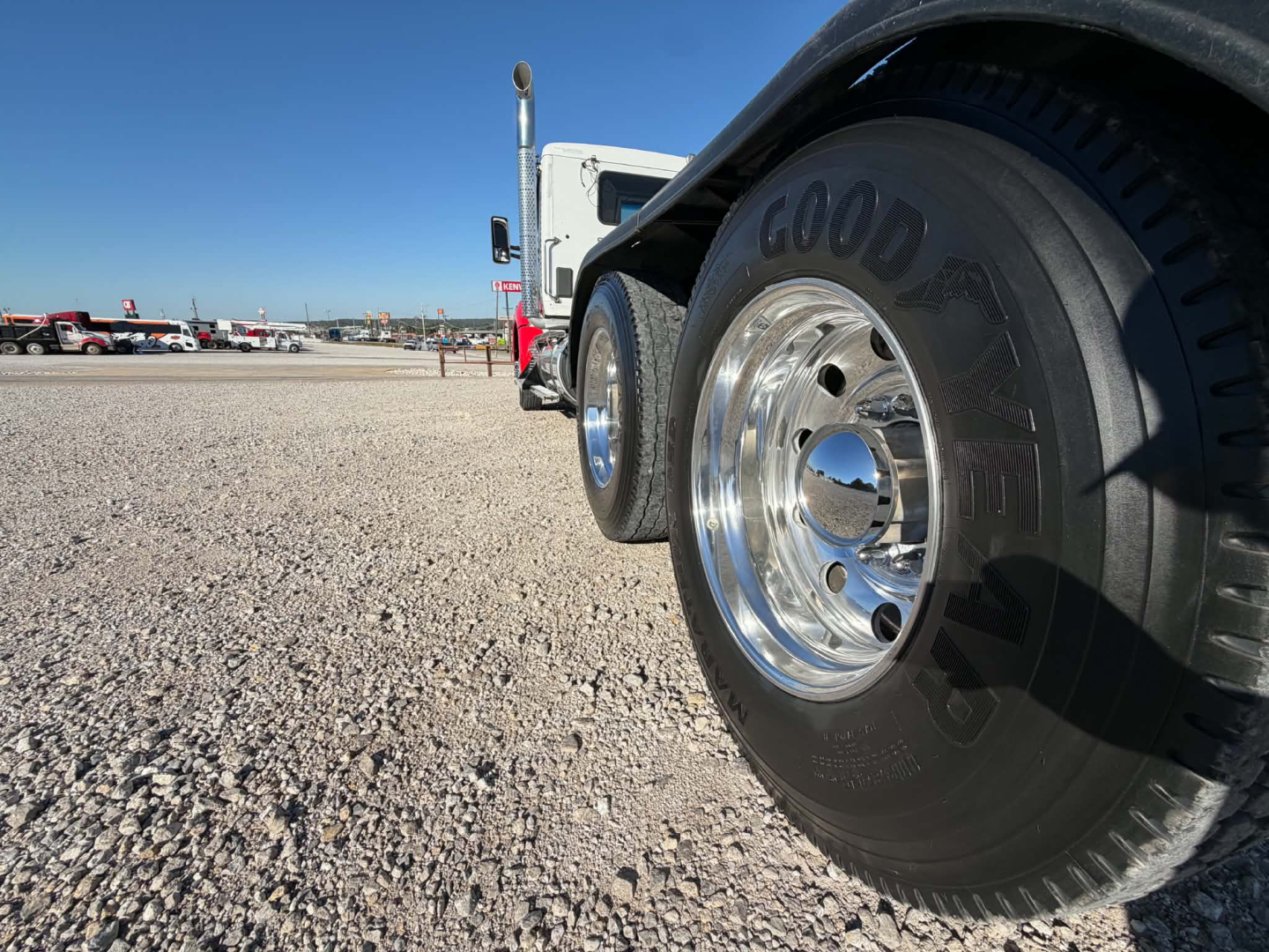 Kenworth T880 wheel and front fender in a used truck lot showing Goodyear tire and shiny chrome rim