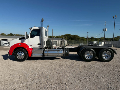 Kenworth T880 daycab chassis side view showing cab with red front fenders, chrome fuel tanks, dual rear axles, and exhaust stack.