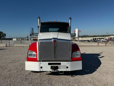 Kenworth T880 front view showing large grille, chrome bumper, dual vertical exhaust stacks, dual headlights, and white front bumper with red fenders.