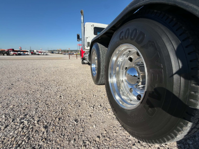 Kenworth T880 wheel and front fender in a used truck lot showing Goodyear tire and shiny chrome rim